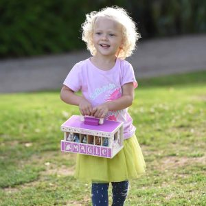 Cheerful girl with curly hair joyfully explores a sunny park with her colorful magic toy.