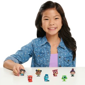 Smiling girl with colorful figurines captures playful creativity and childhood joy at table.