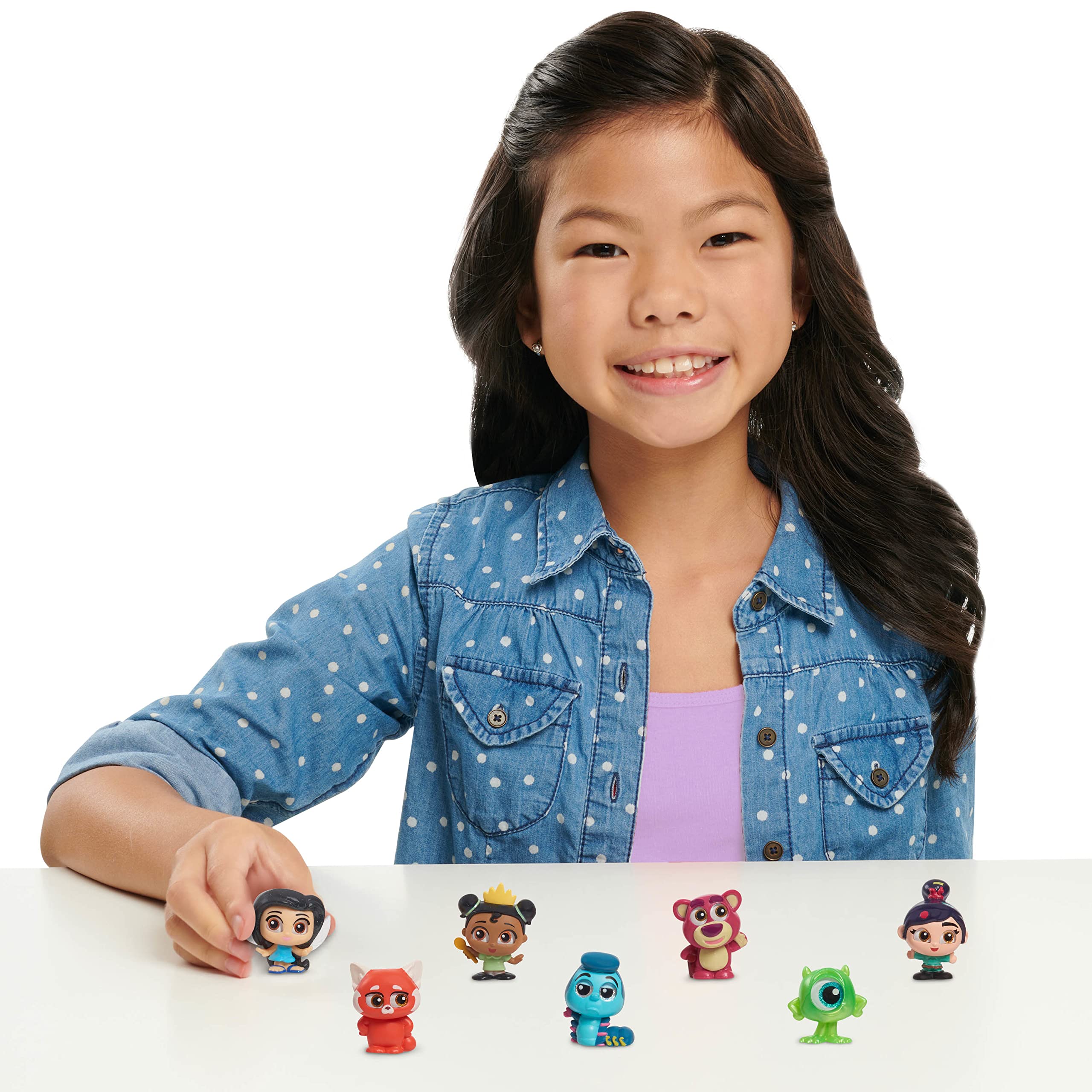 Smiling girl with colorful figurines captures playful creativity and childhood joy at table.