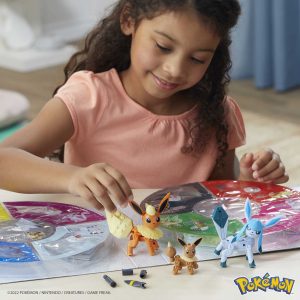 Young girl joyfully creates art with colorful Pokémon figures in a bright playroom.