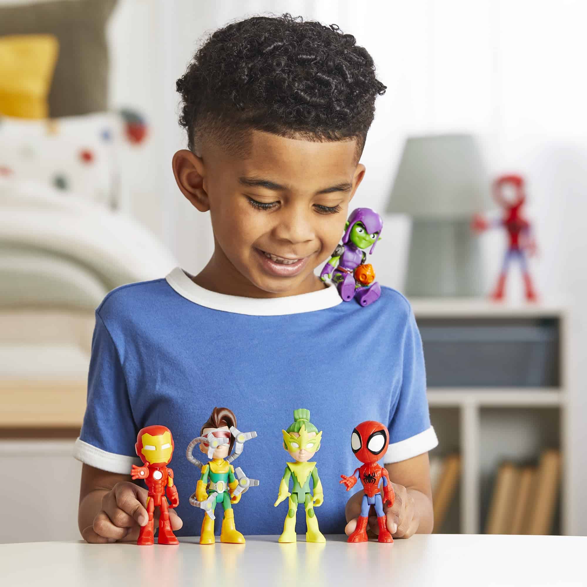 Joyful boy in blue shirt playing with superhero action figures in a colorful playroom.