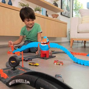 Young boy enjoys imaginative play with a vibrant toy racing track in a bright room.
