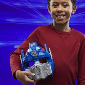 Joyful boy in a red shirt holding a blue hero mask, embodying adventure and imagination.