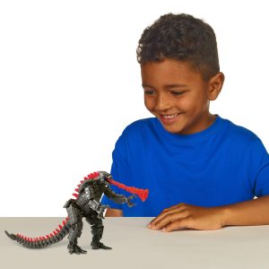 Young boy joyfully plays with a monster toy against a bright, simple background.
