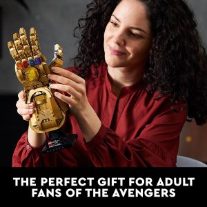 Woman joyfully admires a colorful Marvel Infinity Gauntlet replica, perfect for collectors and fans.
