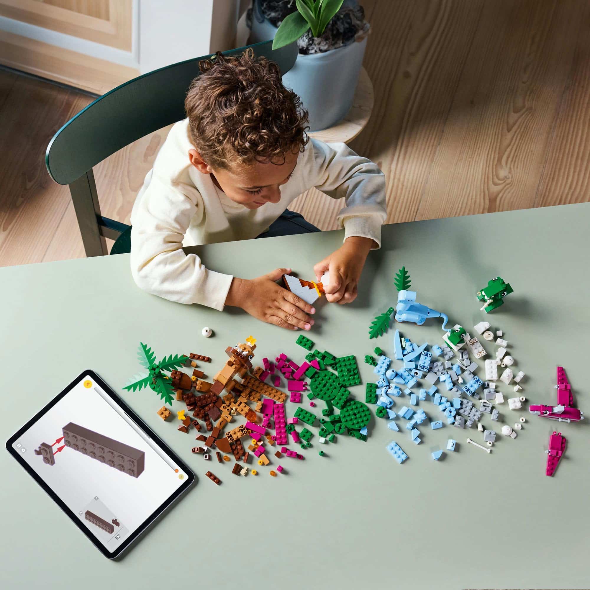 Child engaged in creative play with colorful building blocks and a tablet for guidance.