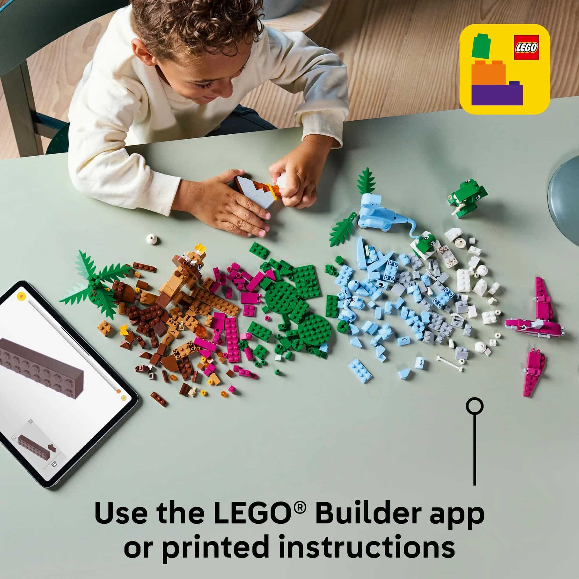 Child focused on colorful LEGO building with tablet-guided instructions for creative play.