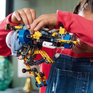 Young child building a colorful Lego vehicle, fostering creativity in a cozy home setting.