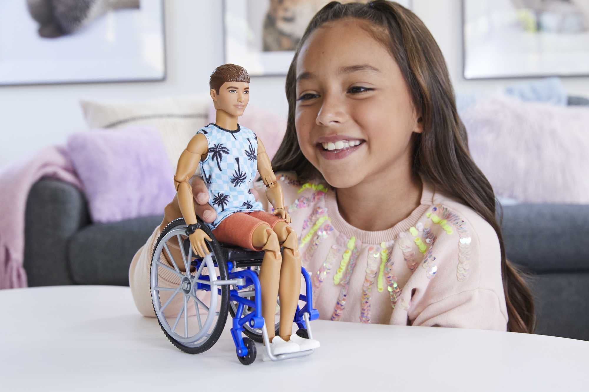 Cheerful girl joyfully plays with her inclusive doll in a wheelchair, promoting diversity in toys.