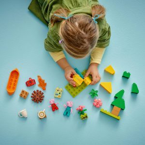 Child playing with colorful building blocks, fostering creativity and imagination on a light blue surface.
