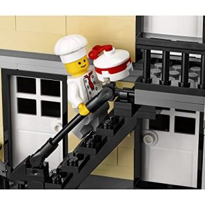 Cheerful LEGO chef climbs stairs with cake, creating a whimsical urban delivery scene.