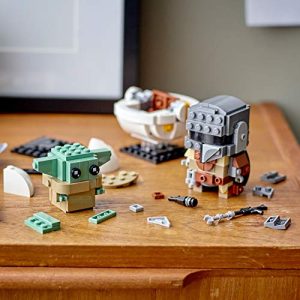LEGO Mandalorian and The Child building scene on a warm wooden surface.