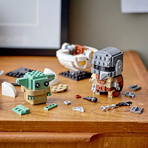 LEGO Mandalorian and The Child building scene on a warm wooden surface.